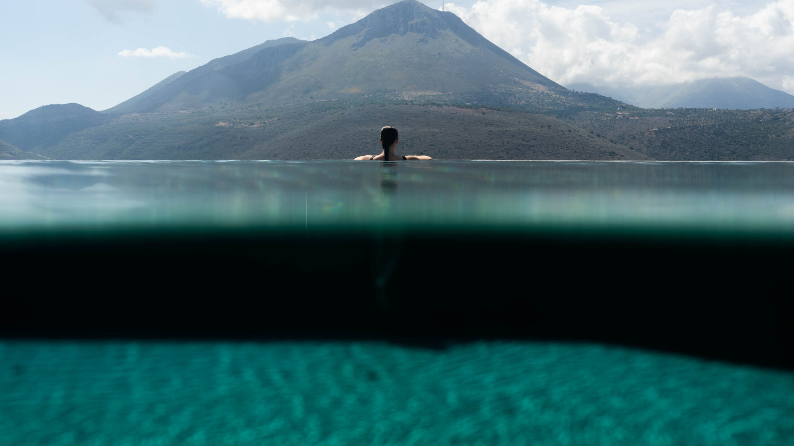Swimmer in the infinity pool at Petra & Fos facing Oitylo Bay and the Mani mountains
